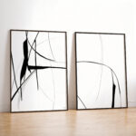 Minimalist black and white abstract line art diptych leaning against white wall on wood floor.