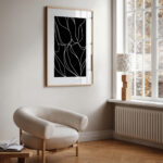 Minimalist living space with black and white botanical art and curved accent chair.
