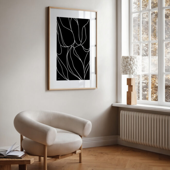 Minimalist living space with black and white botanical art and curved accent chair.