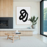 Minimalist black curve abstract art in modern living room with wood paneling and fireplace.