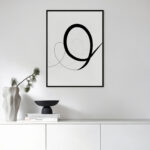 Minimalist black curve art print above white console with simple decor arrangement.