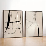 Two minimalist abstract black line artworks in black frames against white wall.