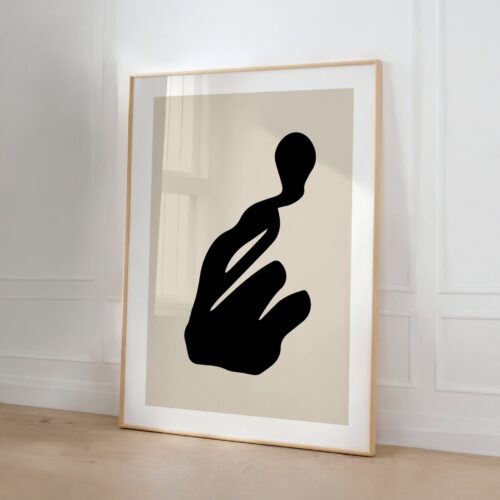 Minimalist black silhouette art print in beige frame leaning against white wall.