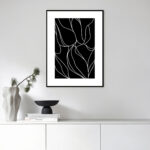 Minimalist black and white floral line art in sleek frame above white cabinet