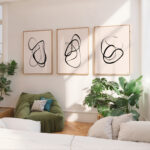 Three minimalist line art prints displayed above a green sofa in bright living room.