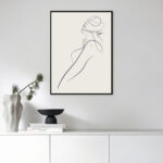 Minimalist line art portrait displayed above styled console with vase and decorative objects.