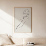 Minimalist female silhouette line art framed above neutral sofa in modern space