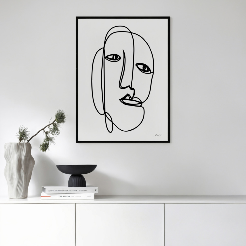 Minimalist black line drawing of abstract face above white cabinet with decorative objects.