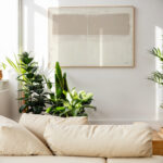 Minimalist living space featuring neutral abstract art, cream sofa, and lush houseplants.