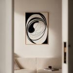 Black and white spiral abstract art print in wooden frame above sofa