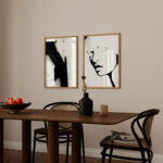 Minimalist dining area with black and white abstract art, dark wood table and cane chairs.