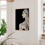 Minimalist black and white female profile artwork on white wall with plant and pendant light.