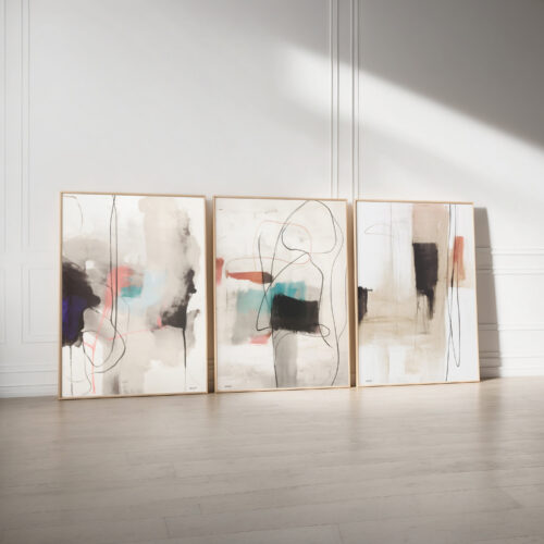 Three abstract art panels in neutral tones leaning against white gallery wall.