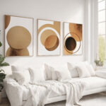 Minimalist abstract geometric trio artwork in earth tones above white couch.