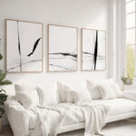 Modern living room featuring minimalist black brushstroke triptych above white sofa.