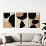 Minimalist black and beige abstract triptych art hanging above gray sofa