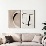 Minimalist abstract line art prints in black and beige above neutral sofa.