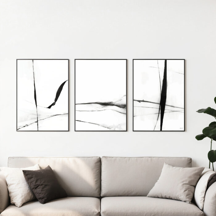Modern black abstract triptych artwork displayed above beige sofa with neutral pillows