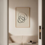 Black abstract line art in minimalist living room with neutral tones and wooden frame.