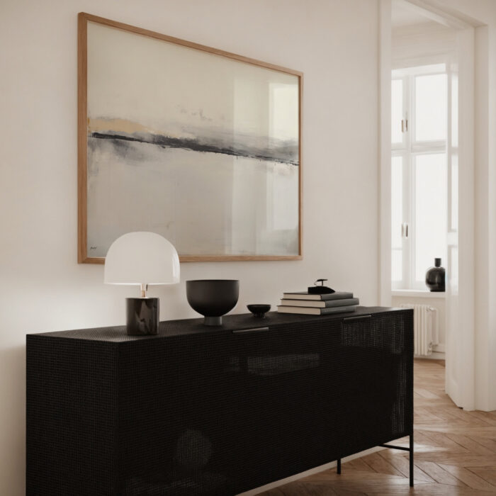 Minimalist black sideboard beneath abstract horizon artwork in bright contemporary interior space.