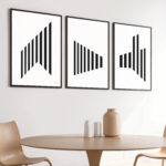 Three framed geometric black and white prints above round wooden table with minimal decor.