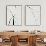 Minimalist black and white curved line art above warm wooden dining table and chairs.