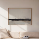 Simple abstract artwork with dark horizontal stroke hanging above beige sofa.