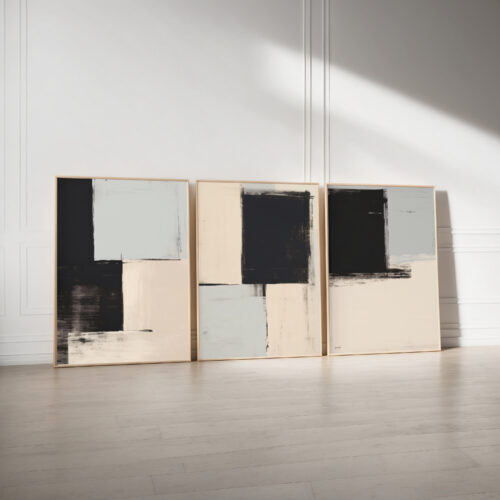 Minimalist triptych art with geometric black, white and beige abstract forms against white wall.