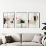 Elegant neutral abstract triptych artwork above beige sofa in contemporary living room