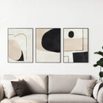 Modern abstract triptych with neutral colors over beige sofa in contemporary living space