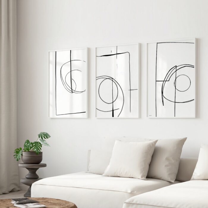 Abstract black line art triptych above white sofa in modern minimalist living room.