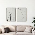 Minimalist black line art prints above beige sofa with decorative pillows and plant.