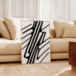 Abstract black and white line art against beige sofa in minimalist living room.