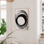Bold black spiral artwork framed on white wall in minimalist modern interior space.