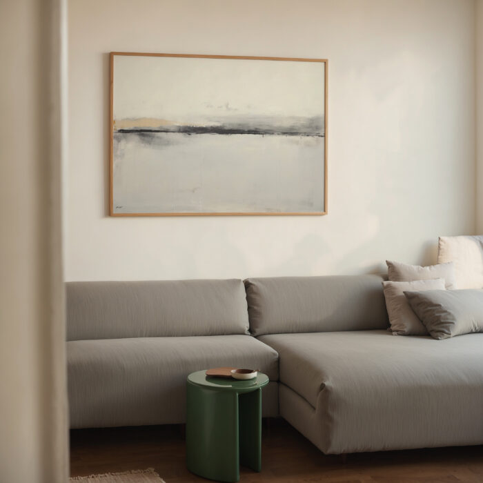 Abstract landscape artwork in muted tones above modern gray sectional sofa.
