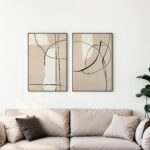 Abstract line art prints in beige and black above neutral-toned sofa.