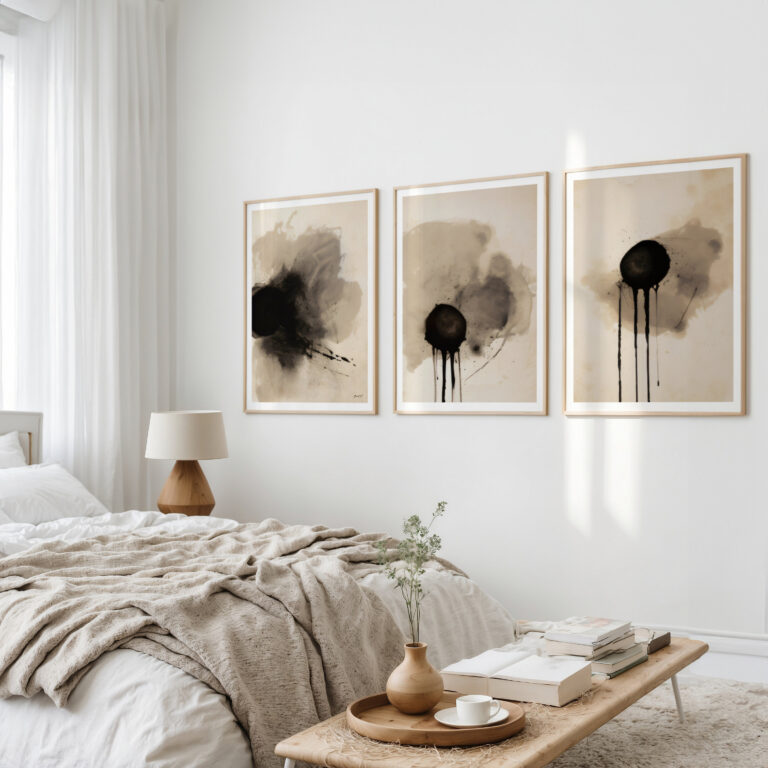 Abstract ink triptych artwork in beige and black tones above minimalist neutral bedroom.