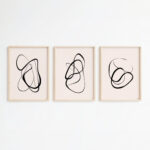 Elegant minimalist triptych with flowing black line art in light wood frames.