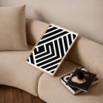Black and white geometric art above light beige sofa in contemporary living space