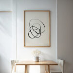Black line abstract art in minimalist interior with wooden furniture and neutral tones.
