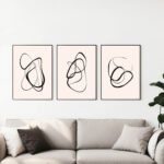 Minimalist black line art displayed above cream sofa with neutral throw pillows.