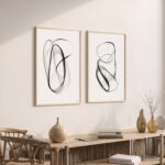 Two framed black abstract art prints above modern wooden console with decorative objects