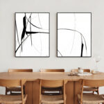 Minimalist black line abstract art prints above wooden dining table with black chairs.