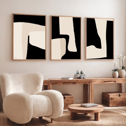 Black and cream abstract triptych art displayed above wooden console with modern chair.