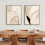 Modern abstract line art prints in neutral tones above wooden dining table.