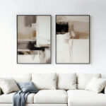 Minimalist abstract art in neutral tones displayed above white sofa in modern living room.