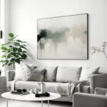 Abstract art above gray sofa in modern minimalist living room with houseplant.