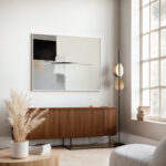 Modern abstract painting above wooden credenza with pampas grass in neutral living room.