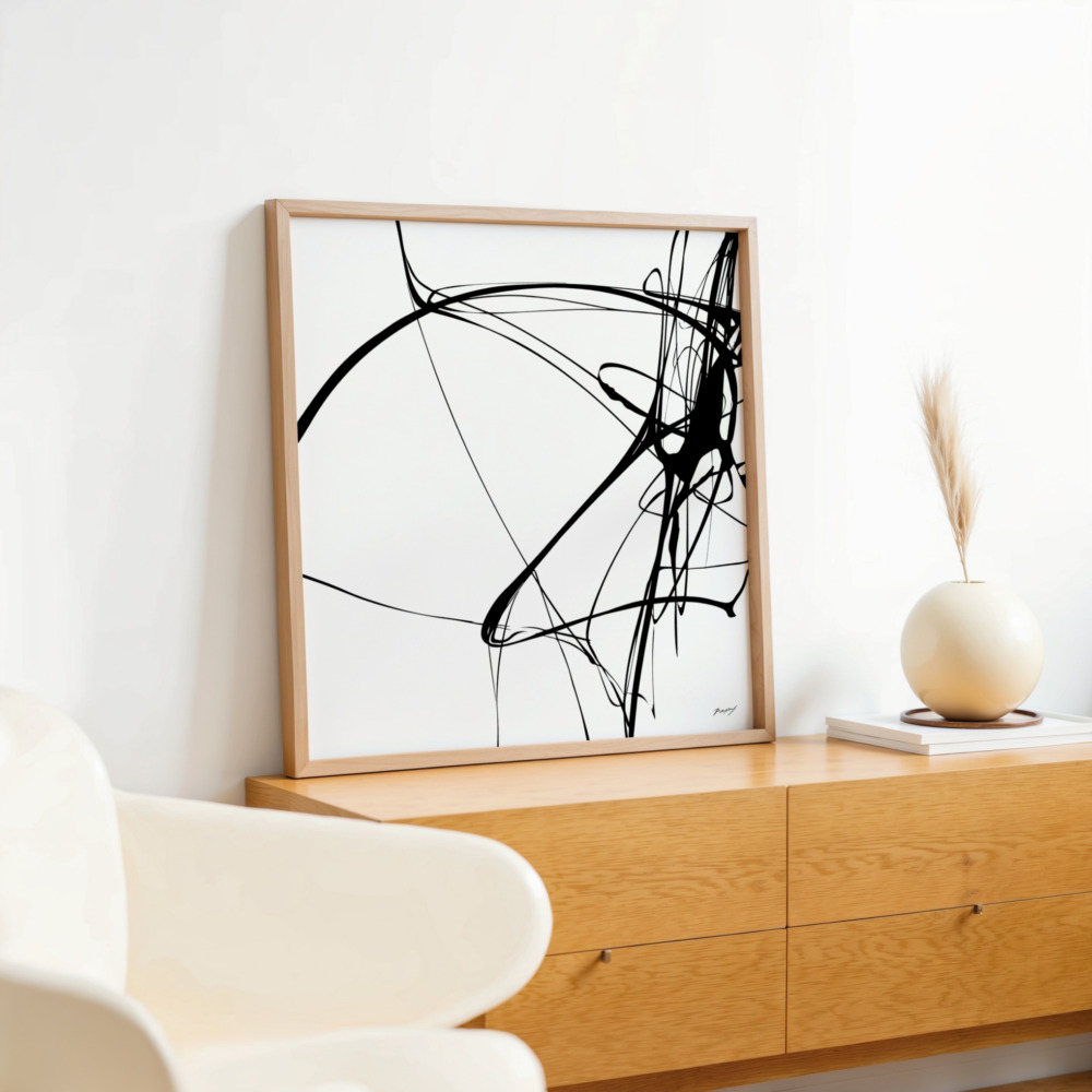 Abstract black brushstroke artwork displayed on wooden sideboard in minimalist interior setting