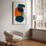 Abstract blue and orange artwork above curved beige chair in minimalist living space
